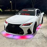 White Lexus car with colorful underglow lights on a dark street.